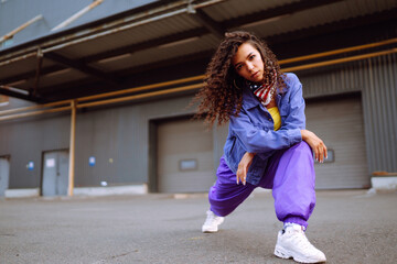 Funky young woman dancing alone in the street. Sport, dancing and urban culture concept. Fashion lifestyle.