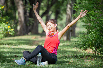 Sport woman breathing deeply fresh air with arms raised outdoor in urban park with blurred background