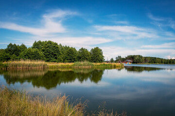 Fototapeta na wymiar A beautiful lagoon with an island in the background. Still water. Krasnobród, Poland