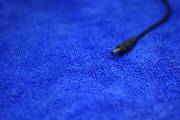DC charger for LED camping light, black wire on micro cloth of blue light.