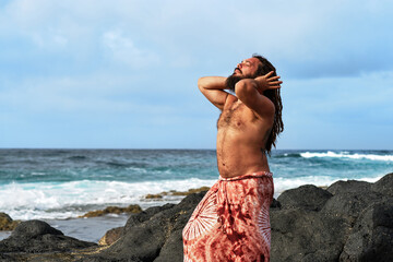 rasta boy with his hair up in the summer, at sunset by the sea