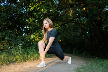 blond sports girl performs elements for stretching the legs, tilting, leaning on the leg and...