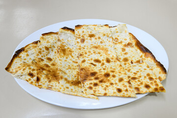 Freshly baked appetizing Turkish tortillas -Gozleme with spinach, cheese  on a wooden board. Shallow depth of  field. Handmade Turkish traditional pastries. Otlu peynirli ispanakli gozleme.