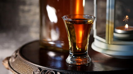 Whisky. Glass of whisky on wood background. Bottle of whisky and candle on old wooden table.