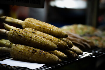 Delicious burnt fire grilled sweet yellow corn , Asian Night street food market.
