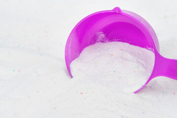 Laundry detergent for washing machines and a plastic scoop for dosing. Washing powder with measuring spoon. White wash powder with with colored granules