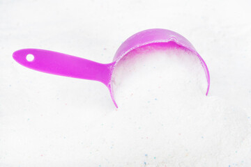Laundry detergent for washing machines and a plastic scoop for dosing. Washing powder with measuring spoon. White wash powder with with colored granules