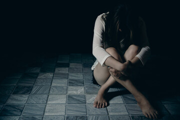 Young person woman sad, stress and loneliness sitting in dark room, Unhappy and crying teenage girl...
