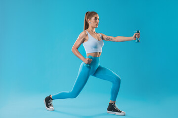 Fototapeta na wymiar Trainer girl in blue clothes doing a one foot squat on a light blue background.
