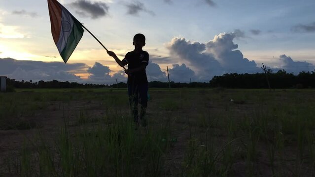 
little Boy holding tri colour national Indian flag in the nature & waving flag in the air. Independence Day - Holiday and Republic Day