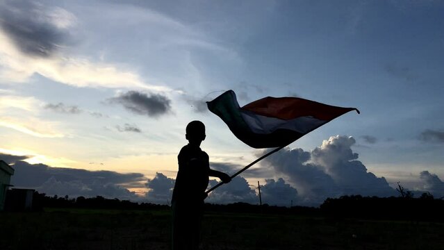 
little Boy holding tri colour national Indian flag in the nature & waving flag in the air. Independence Day - Holiday and Republic Day
