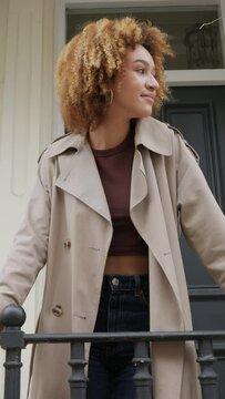 Young woman in a trench coat walks through the city streets