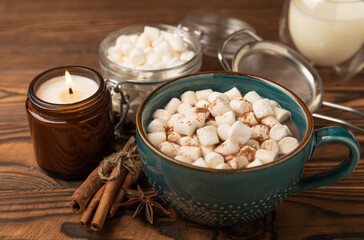 Cup of tasty cocoa drink and marshmallows in blue cup.Spices and marshmallows for winter drinks on brown texture table.Winter hot drink.Hot chocolate with marshmallow and spices.Copy space.