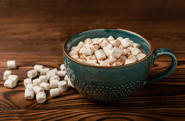 Cup of tasty cocoa drink and marshmallows in blue cup.Spices and marshmallows for winter drinks on brown texture table.Winter hot drink.Hot chocolate with marshmallow and spices.Copy space.