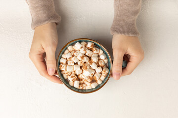 Cup of tasty cocoa drink and marshmallows in hands.Spices and marshmallows for winter drinks on a textured background.Winter hot drink.Hot chocolate with marshmallow and spices.Copy space.