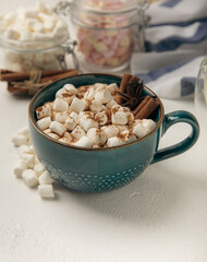 Cup of tasty cocoa drink and marshmallows in blue cup.Spices and marshmallows for winter drinks on white texture table.Winter hot drink.Hot chocolate with marshmallow and spices.Copy space.