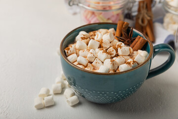 Cup of tasty cocoa drink and marshmallows in blue cup.Spices and marshmallows for winter drinks on white texture table.Winter hot drink.Hot chocolate with marshmallow and spices.Copy space.