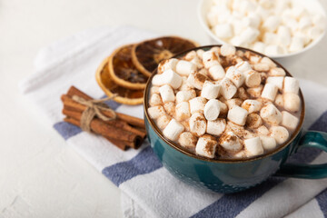 Cup of tasty cocoa drink and marshmallows in blue cup.Spices and marshmallows for winter drinks on white texture table.Winter hot drink.Hot chocolate with marshmallow and spices.Copy space.