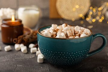 Cup of tasty cocoa drink and marshmallows in blue cup.Spices and marshmallows for winter drinks on black texture table.Winter hot drink.Hot chocolate with marshmallow and spices.Copy space.