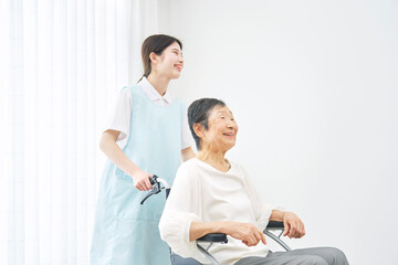 Obraz na płótnie Canvas 介護施設でシニア女性の乗る車椅子を押す介護士