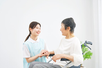 介護施設で車椅子に乗るシニア女性と会話する介護士