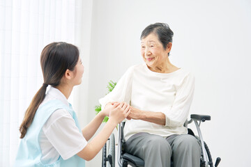 介護施設で介護士と会話する車椅子に乗るシニア女性