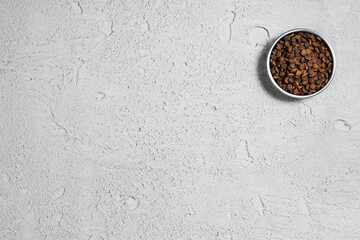 Dry dog pet food in bowl and accessories on gray concrete background top view. Pet feeding and care concept background with copy space. Photograph taken from above.