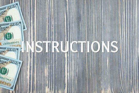 INSTRUCTIONS - word (text) on wooden background, money, dollars. Business concept (copy space).