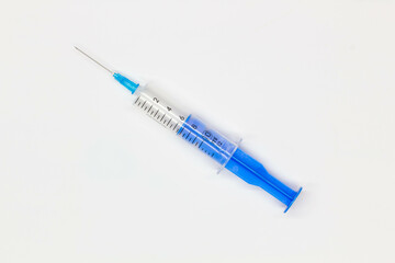 Blue medical disposable syringe for injection on a white background. Medical instrument for vaccination. 10 ml syringe for COVID-19 vaccine. Medical equipment. Isolated. Top view. Close-up 
