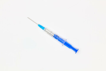 Fototapeta premium Blue medical disposable syringe for injection on a white background. Medical instrument for vaccination. 2 ml syringe for COVID-19 vaccine. Medical equipment. Isolated. Top view. Close-up 