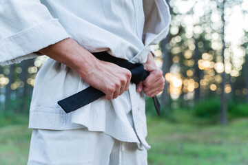 A young guy doing karate training and meditation in the forest during the day