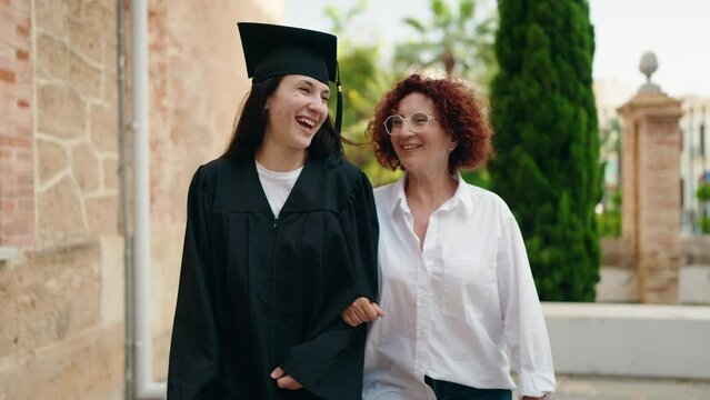 Two women mother and daughter celebrating graduation walking at campus university
