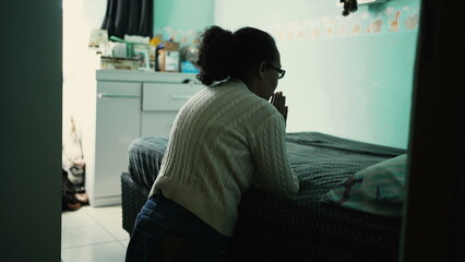 One hispanic older woman praying by the bedside. Religious elder person in FAITH prayer