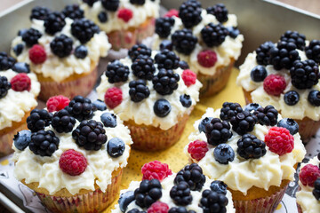 Homemade cupcakes decorated white cream and wild berries, delicious and fresh,