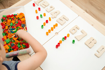 Math with fun. Calculation and marking of uncooked pasta with colored natural wood numbers. Do-it-yourself game. Play at home. The way of learning. Early education, counting game, fine motor skills.