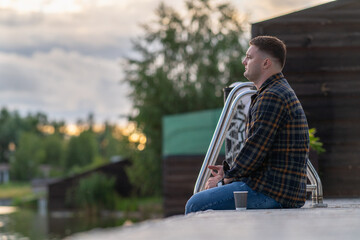 Young man sitting on a wooden boardwalk at sunset