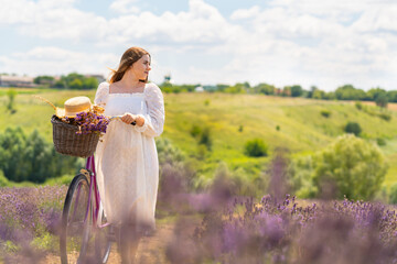 Young country woman wheeling her bicycle through lavender fields