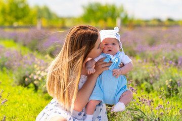 Loving mother kissing her baby son outdoors in summer