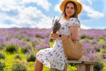 Pretty fashionable young woman sitting in a lavender field