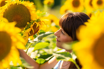 Attractive woman admiring a vibrant yellow sunflower in a field