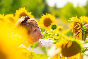 Attractive blond middle aged woman in a field of sunflowers