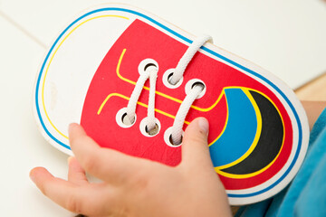 Wooden Shoe Toy. Game to learn how to tie shoe laces. Kids hands on. Primary education. Montessori methodology. Implement for fine motor skils and hand coordination.