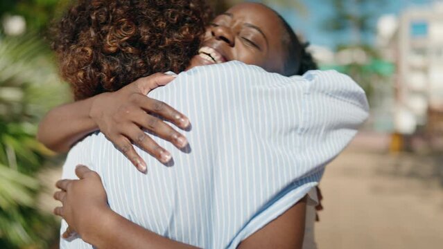 African american women mother and daughter hugging each other at park