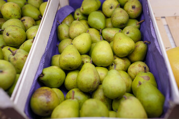 Green pears in box in grocery department of supermarket, store, shop, shopping center. Sweet summer fruit Close up shot