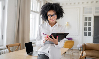 An economist a woman with glasses works uses a laptop in the office makes a report with documents...