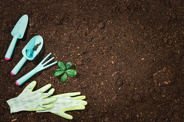 Gardening tools on fertile soil texture background seen from above, top view. Gardening or planting concept. Working in the spring garden. Flat lay mockup with border composition