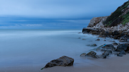 Fototapeta na wymiar rocks in the calm and cloudy sea minimalism