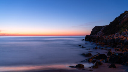 Fototapeta na wymiar rocks in the calm sea dawning minimalism