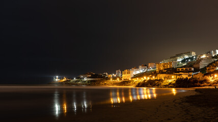 Fototapeta na wymiar view of a coastal town at night with reflections in the water
