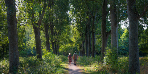 Couple walking on path in a forest in summer in Broekpolder, Vlaardingen, Netherlands